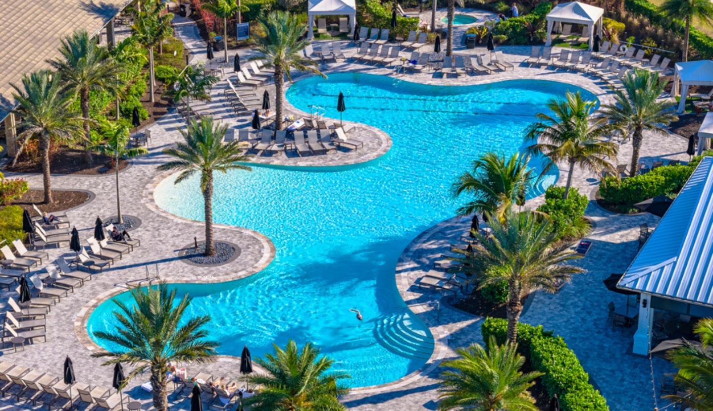 Aerial view of the resort-style zero-entry pool at Esplanade, ringed by palms, lounge chairs and covered cabanas