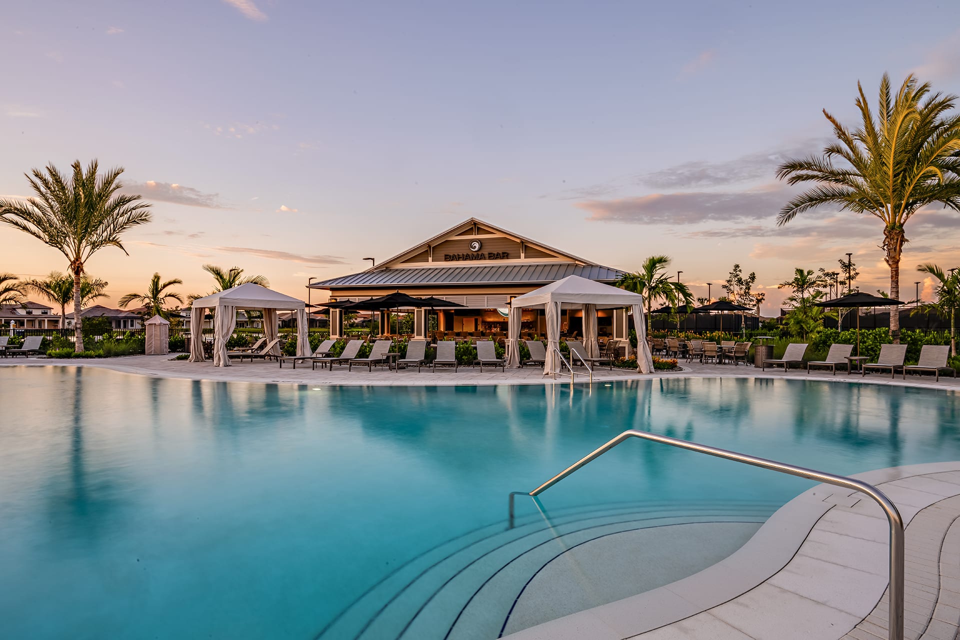 The resort-style zero-entry pool at Esplanade at dusk, with cabanas, lounge chairs and the Bahama Bar behind it